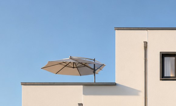 Dachterrasse des Neubaus mit Sonnenschirm vor blauem Himmel